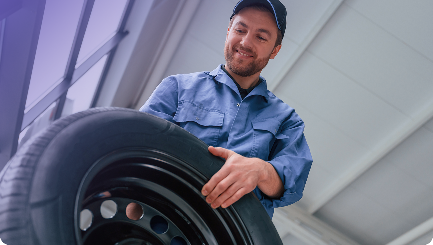 Mecânico segurando pneu em oficina automotiva